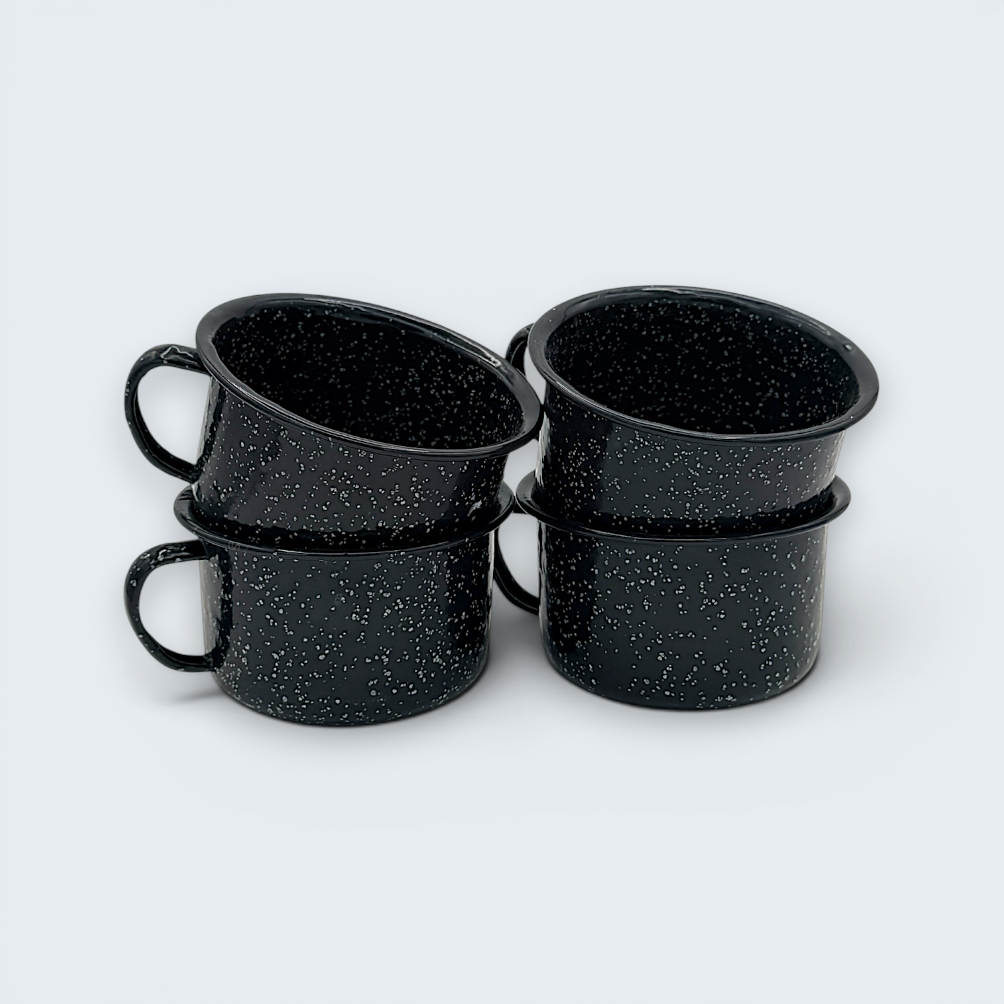 A vintage black enamel cup with white speckles and a single handle, showing a rustic interior with character-building wear at the bottom. - Photo 1