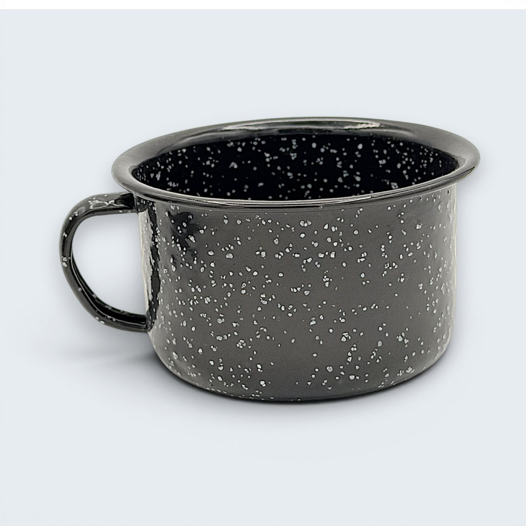 A vintage black enamel cup with white speckles and a single handle, showing a rustic interior with character-building wear at the bottom. - Photo 3