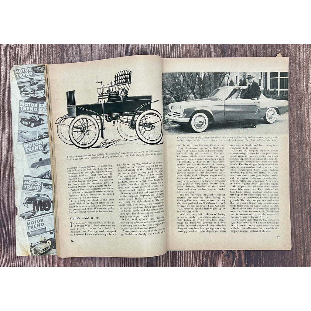 Open book with vintage car illustrations and text on a wooden surface
