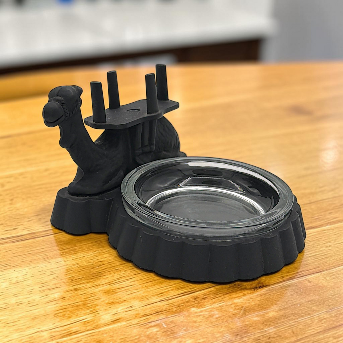 A black cast iron camel figurine featuring a four-prong saddle holder for cigarette packs, attached to a scalloped base with a removable clear glass ashtray dish. - Photo 7