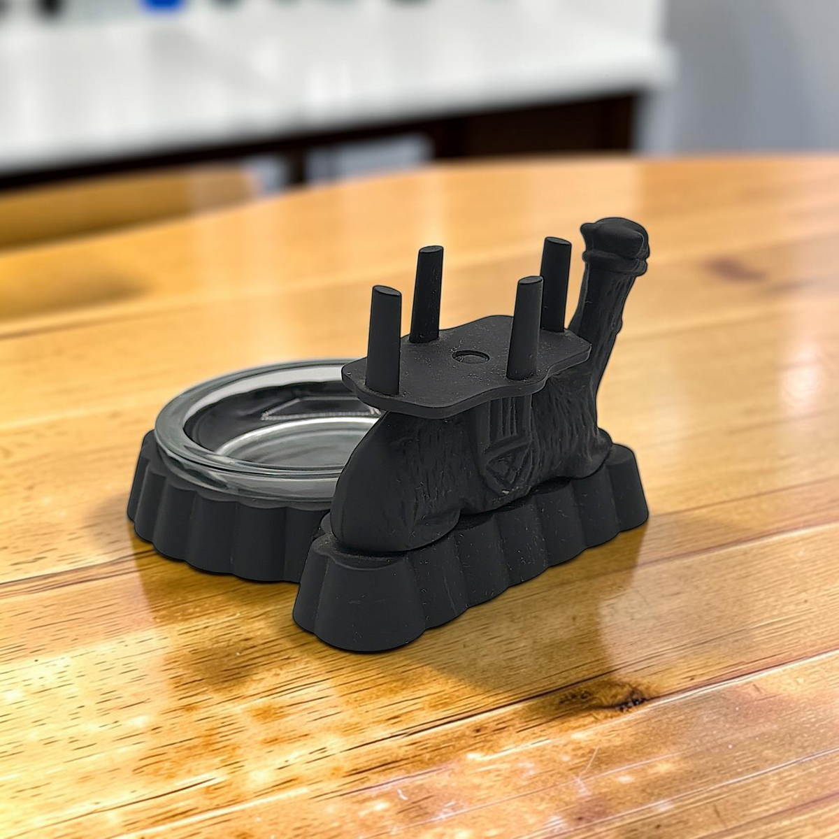 A black cast iron camel figurine featuring a four-prong saddle holder for cigarette packs, attached to a scalloped base with a removable clear glass ashtray dish. - Photo 8