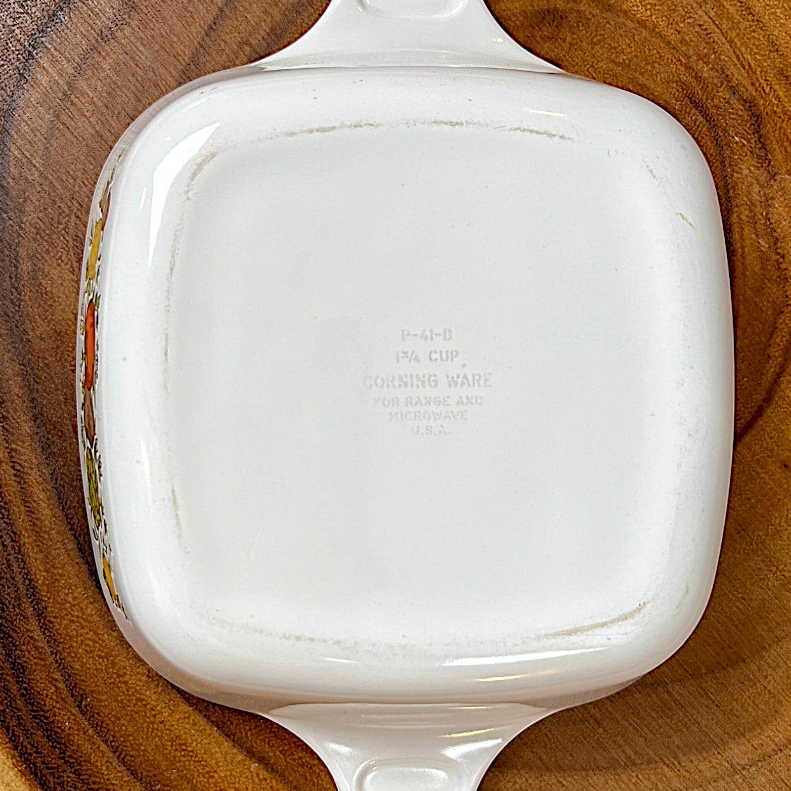 A square-shaped white Corning Ware petite casserole dish with lug handles, resting on a rustic wood slice background. - Photo 2