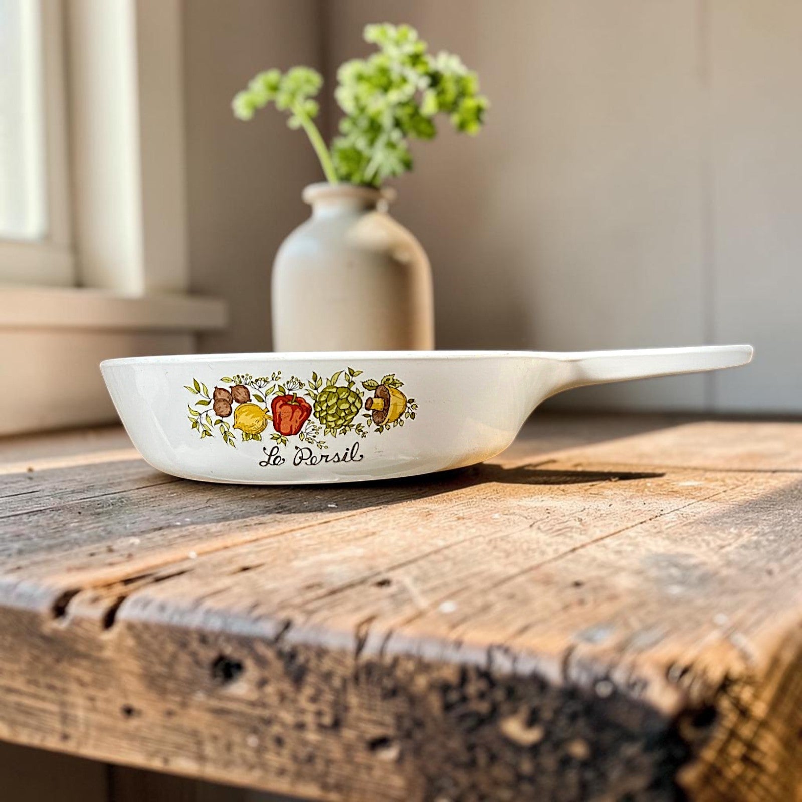 A vintage white Corning Ware P-83-B skillet pan with an integrated handle, resting on a round wooden cutting board. - Photo 1