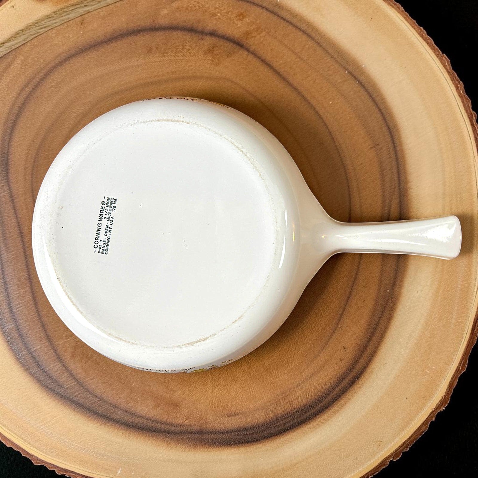 A vintage white Corning Ware P-83-B skillet pan with an integrated handle, resting on a round wooden cutting board. - Photo 3