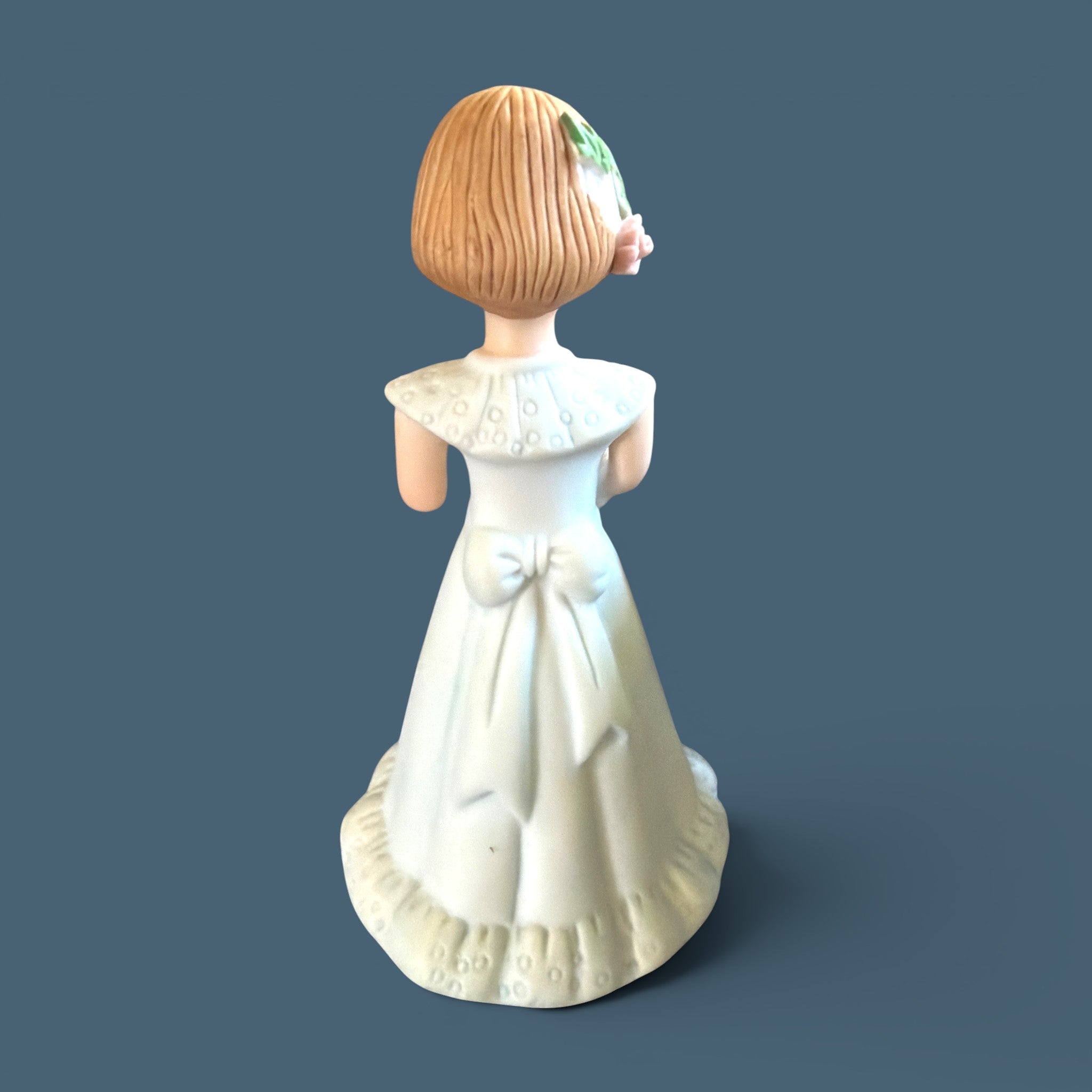 Vintage Enesco Growing Up Girls Age 6 porcelain figurine showing a fair child wearing a delicate white floor-length dress decorated with a classic high collar, a soft ruffled hemline, and a prominent bow tied at the back. - Photo 3