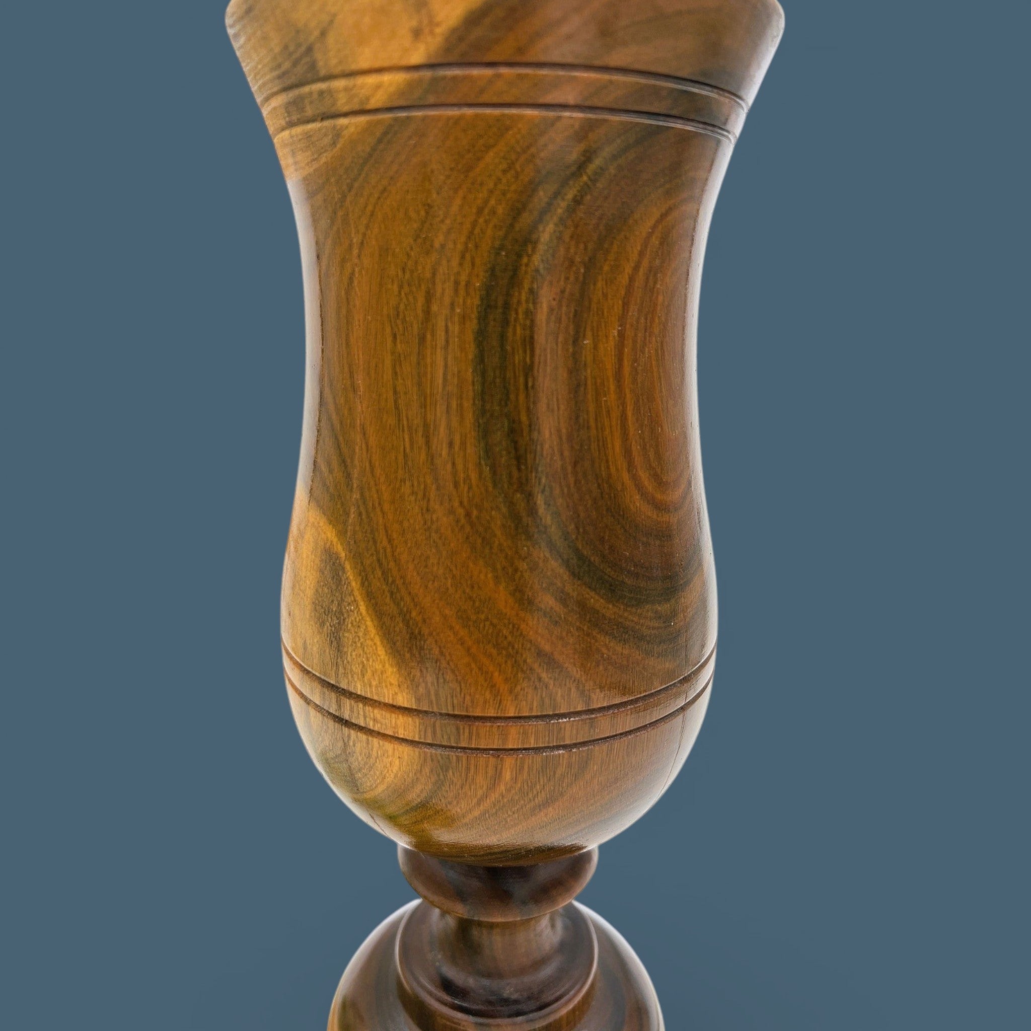 A vintage hand-turned wood chalice vase with a flared rim and a stout pedestal base, displaying a highly figured grain with rich brown and golden hues and fine concentric incised lines around the body against a solid dark grey background. - Photo 4