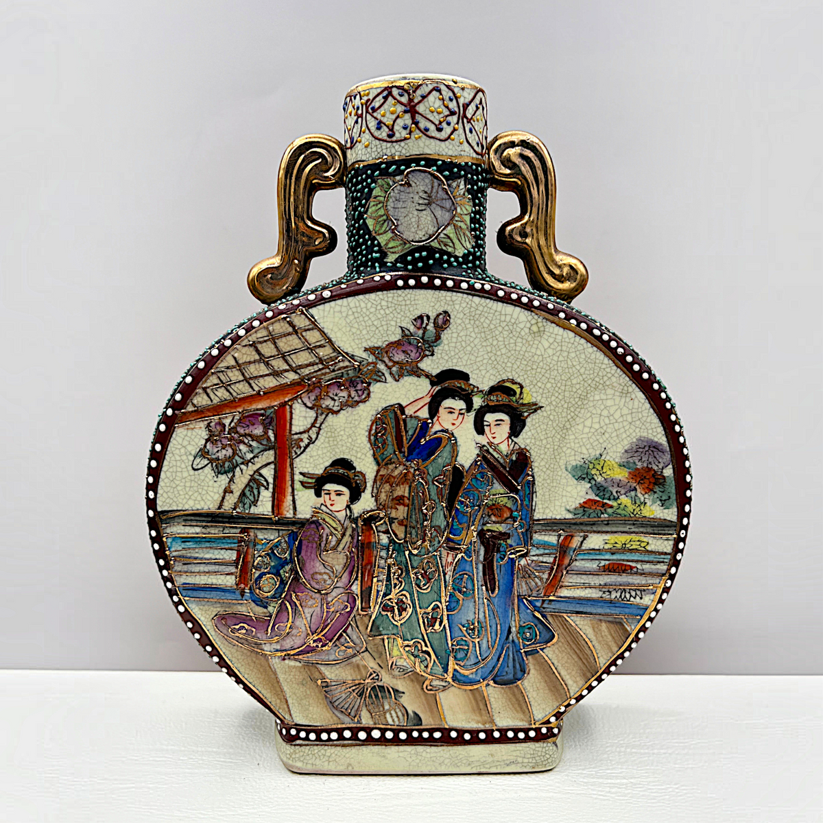 Japanese Satsuma ceramic moon flask vase with gilded scroll handles, fine cream crackle glaze, and hand-painted geisha figures in colorful kimonos surrounded by raised moriage enamel beading along the shoulders and borders. - Photo 1