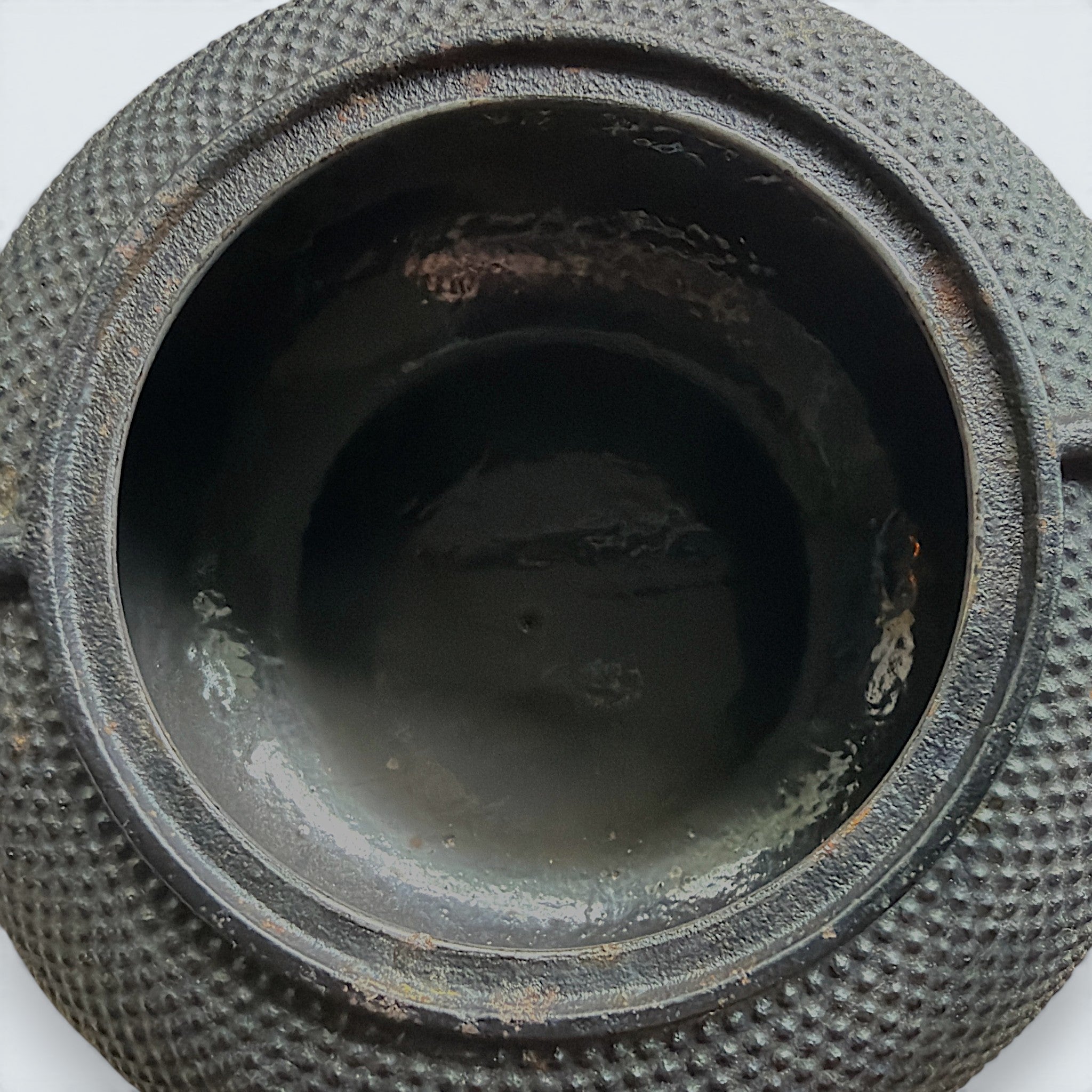 A black cast iron tetsubin teapot featuring a classic hobnail textured surface, open top showing a stainless steel mesh infuser basket, and two pivoting black metal handle hinges on the sides. - Photo 9