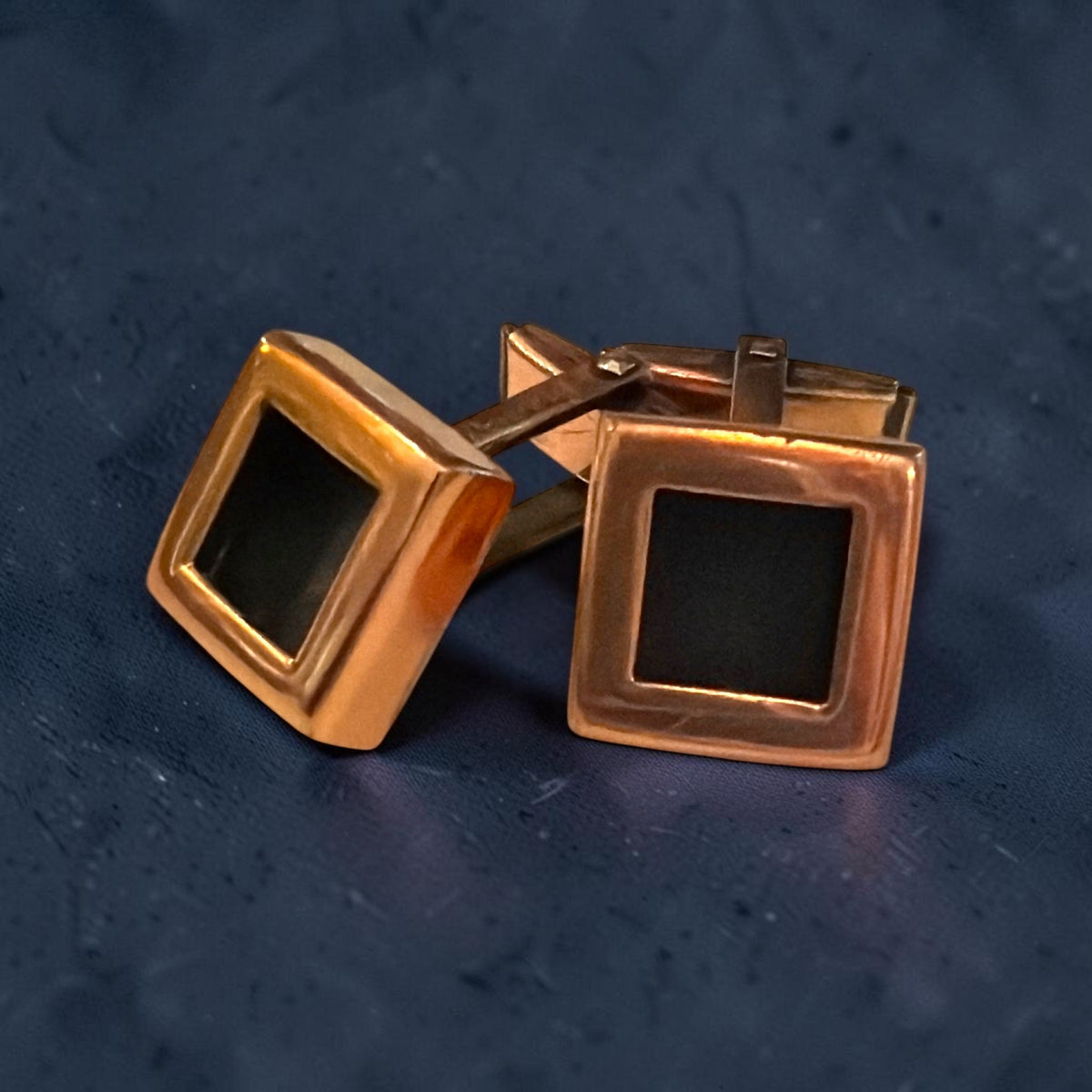 A pair of vintage Mid-Century Modern copper cufflinks featuring clean square faces with recessed black geometric centers and swivel bar toggles. - Photo 1