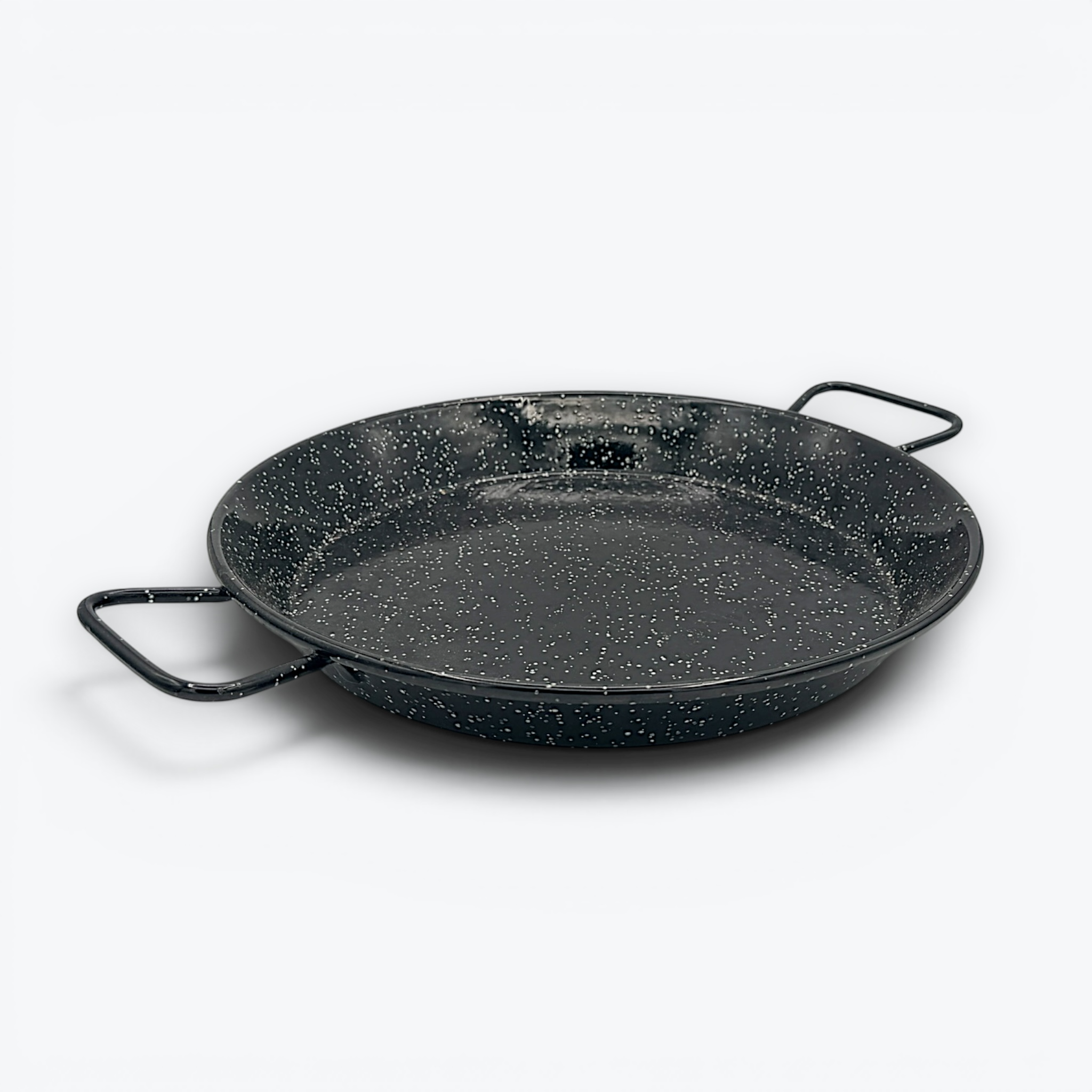 A round, shallow black enamelware paella pan with a white speckled pattern and two wire handles on opposite sides, displayed against a clean white background. - Photo 1