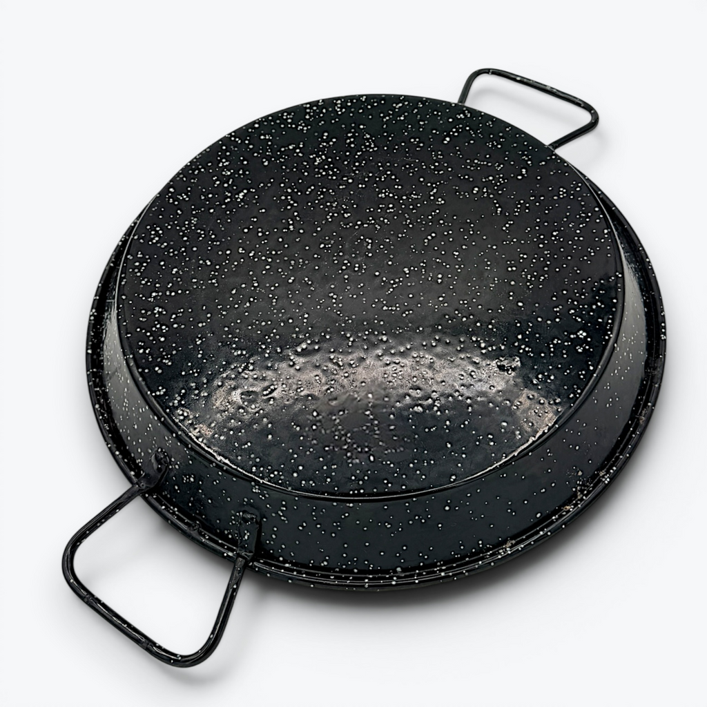 A round, shallow black enamelware paella pan with a white speckled pattern and two wire handles on opposite sides, displayed against a clean white background. - Photo 2