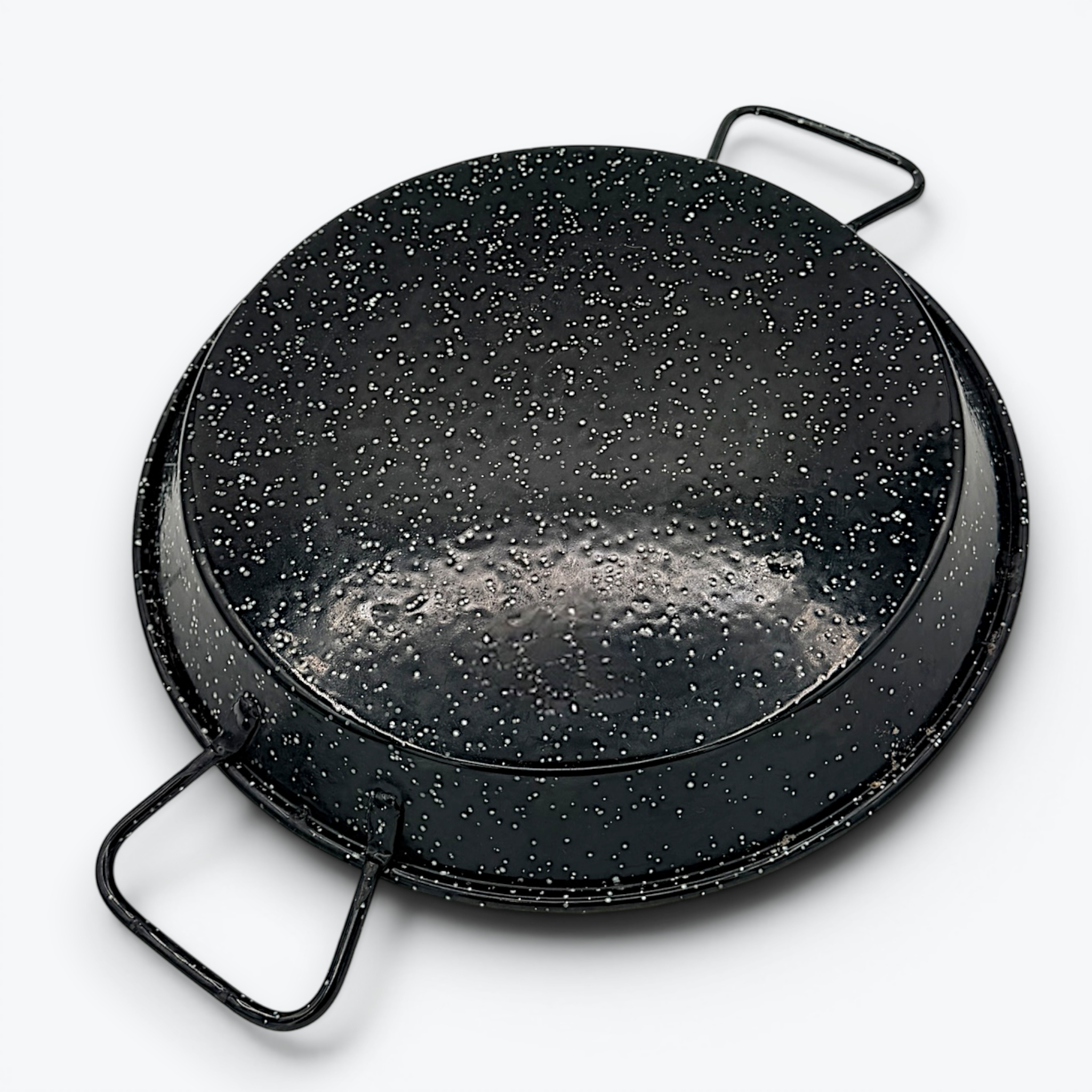 A round, shallow black enamelware paella pan with a white speckled pattern and two wire handles on opposite sides, displayed against a clean white background. - Photo 2