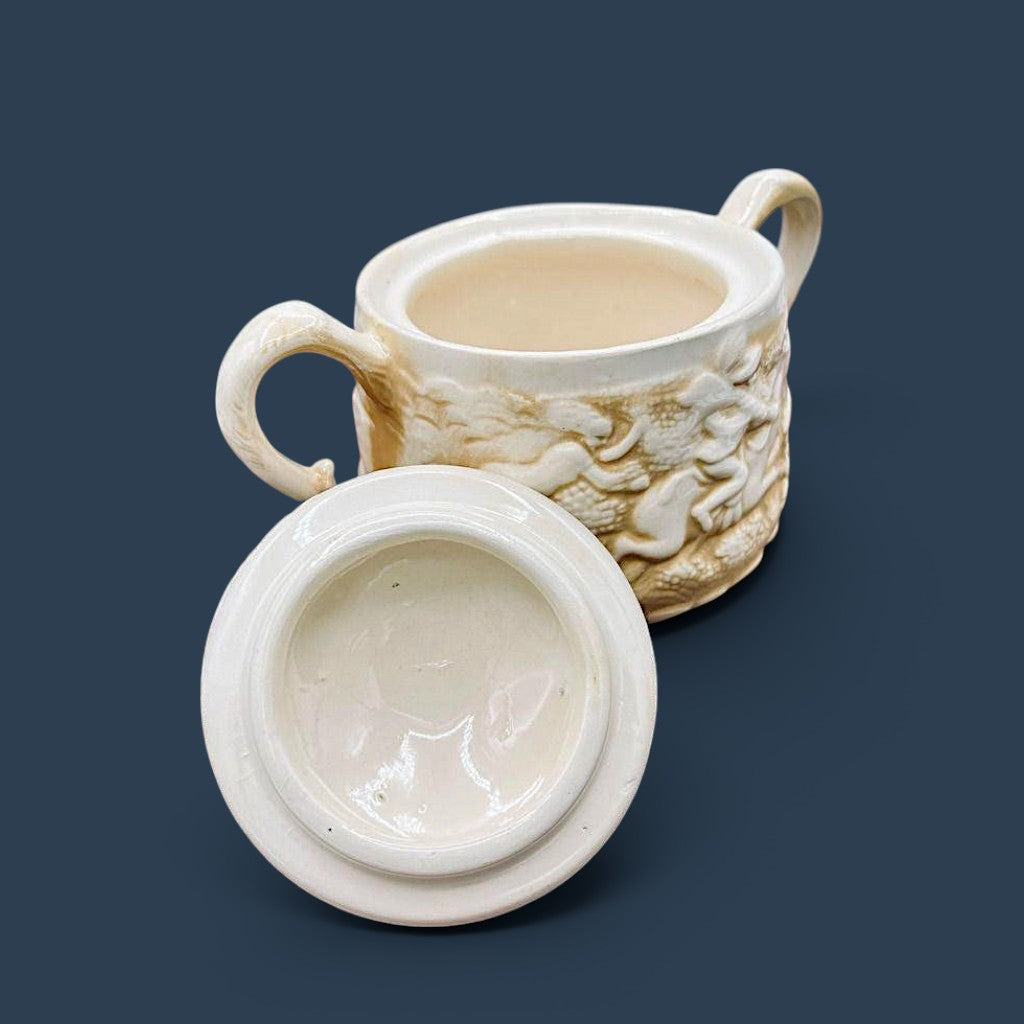 A cream-colored antique ceramic creamer pitcher featuring detailed relief-molded scenes of tavern figures under a smooth glazed finish. - Photo 3
