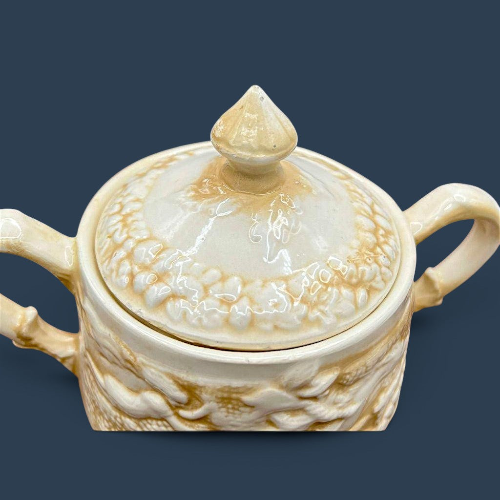 A cream-colored antique ceramic creamer pitcher featuring detailed relief-molded scenes of tavern figures under a smooth glazed finish. - Photo 4