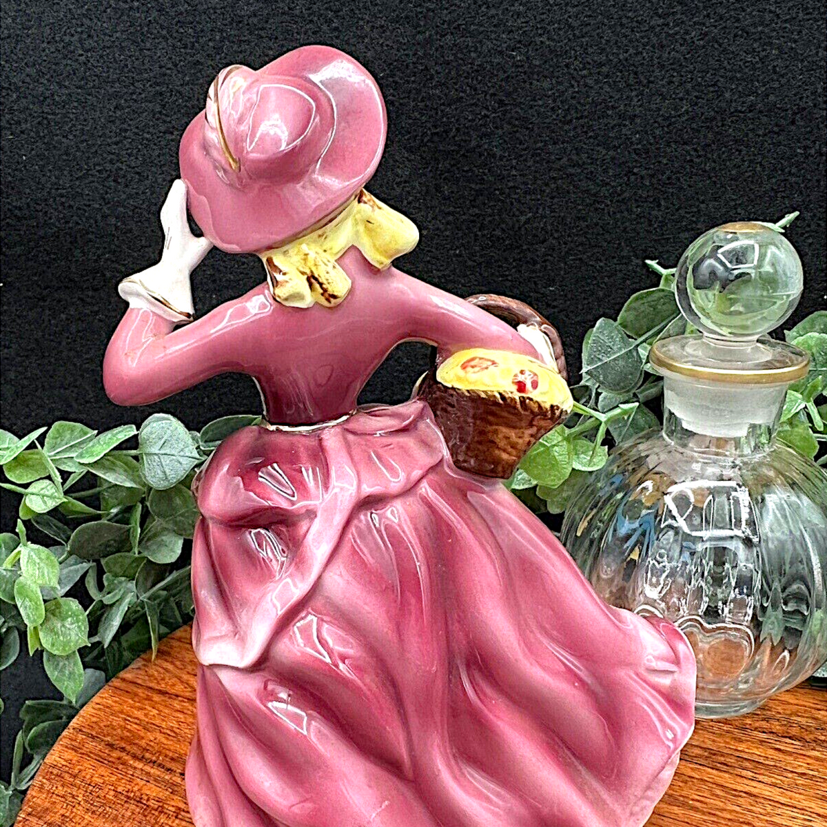 Vintage Ucagco ceramic figurine of an elegant Victorian lady wearing a glossy mauve dress, wide-brimmed bonnet, and white gloves while carrying a flower basket. - Photo 3
