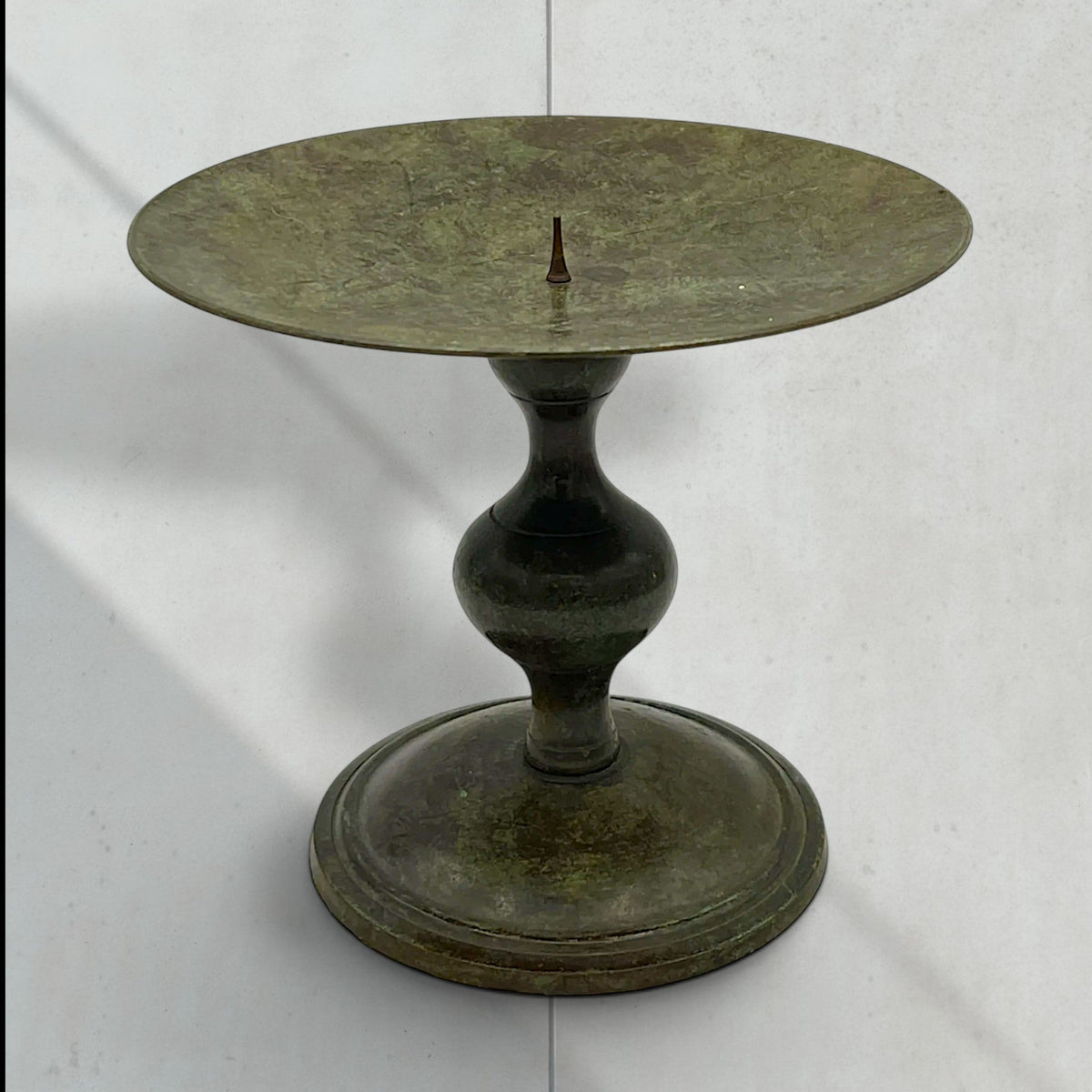 Vintage green verdigris patinated bronze pricket candlestick holder with a wide dished drip pan, central candle spike, and turned baluster stem resting on a circular stepped base. - Photo 1