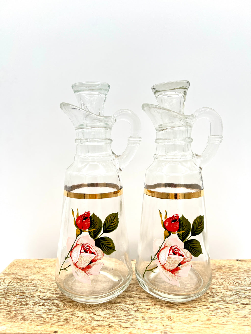 A pair of clear glass cruets with stoppers, featuring hand-painted pink and red roses with green leaves and a gold-gilded band around the neck. - Photo 5
