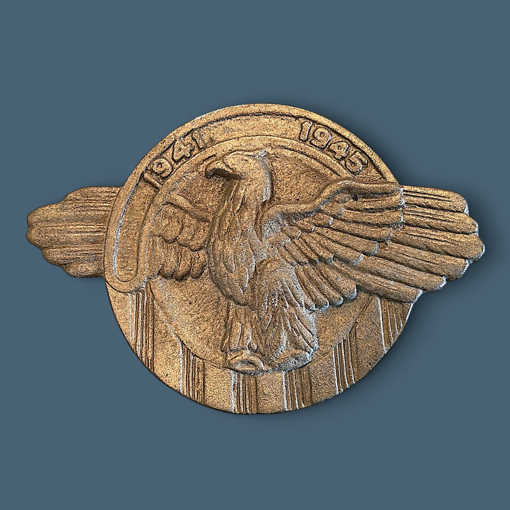 A vintage cast metal World War II commemorative eagle emblem plaque featuring a stylized American eagle with outstretched wings perched above vertical stripes and an arched banner reading 1941 1945 in a warm bronze finish. - Photo 1