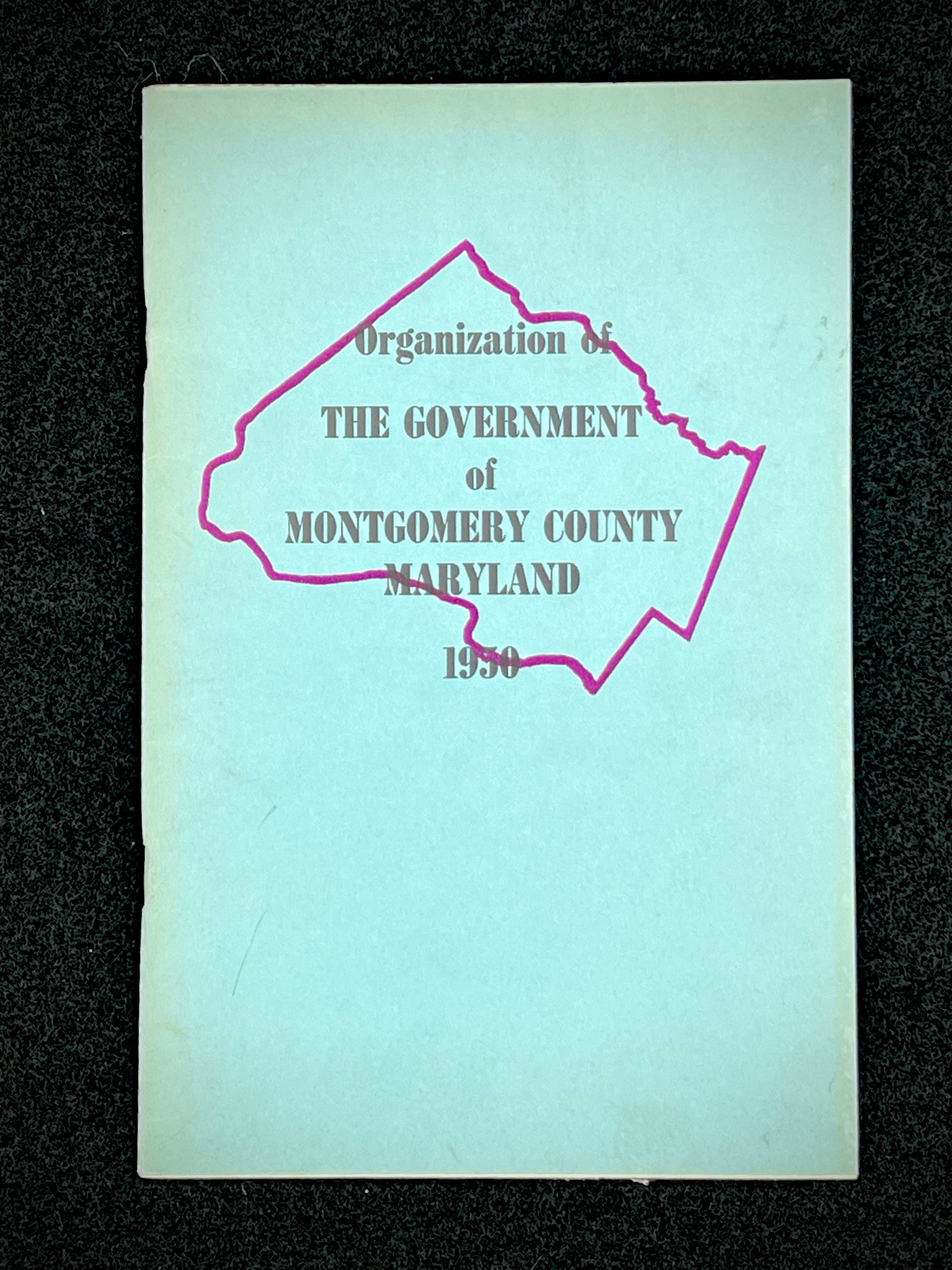 A light blue vintage paper cover of a mid-century Montgomery County Maryland historical publication resting flat on a dark background. - Photo 13